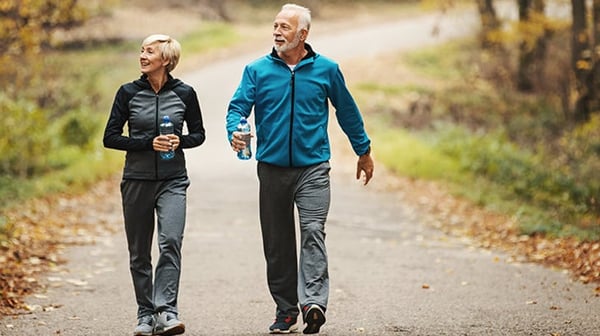 two mature people walking through the woods